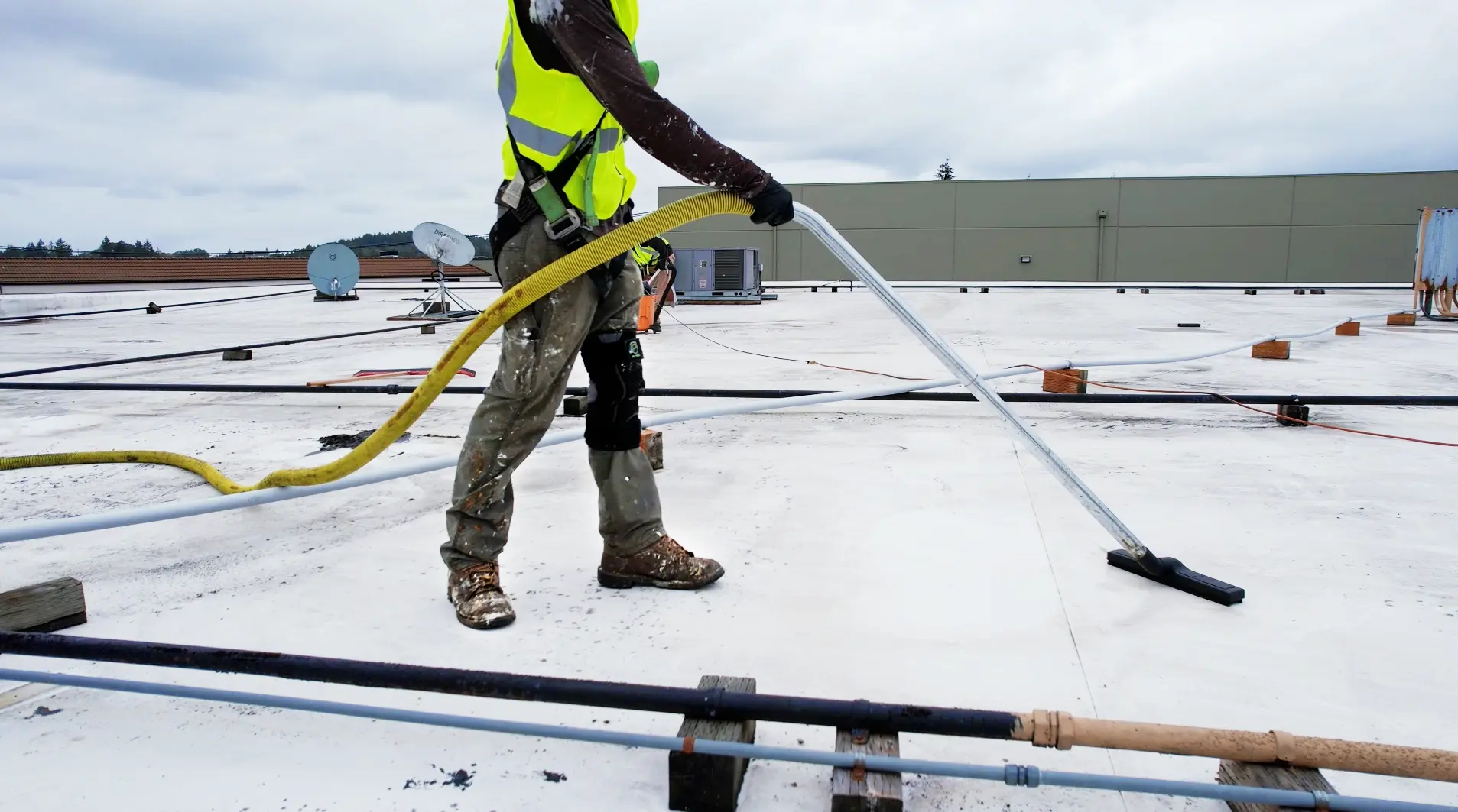 Flat Roof Pros technician cleaning commercial flat roof membrane with pressure washer — removing dirt and organic buildup for improved performance.
