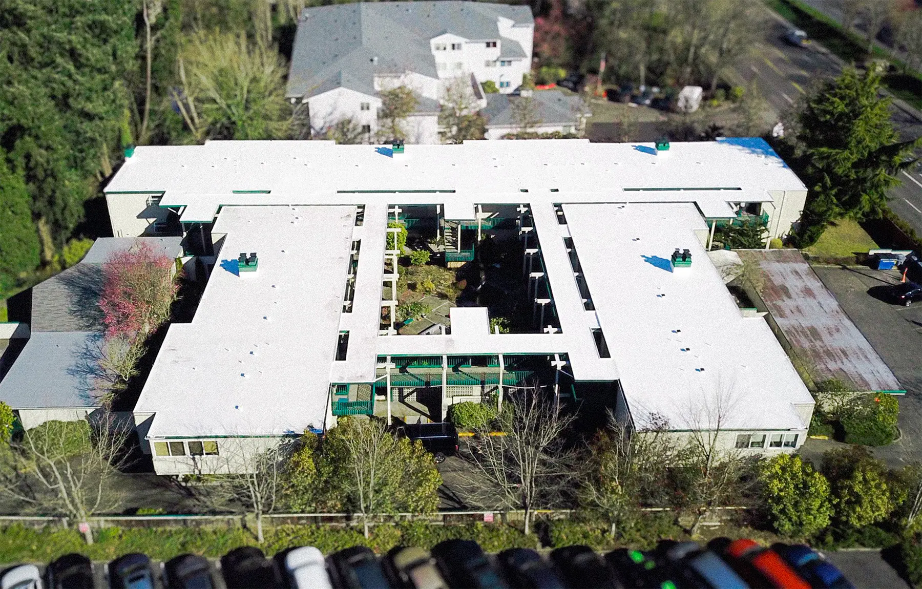 Flat Roof Pros completed commercial flat roof replacement on multi-wing facility — white TPO membrane roofing installed to improve insulation, waterproofing, energy efficiency, and low-slope roof performance in a large-scale building project.