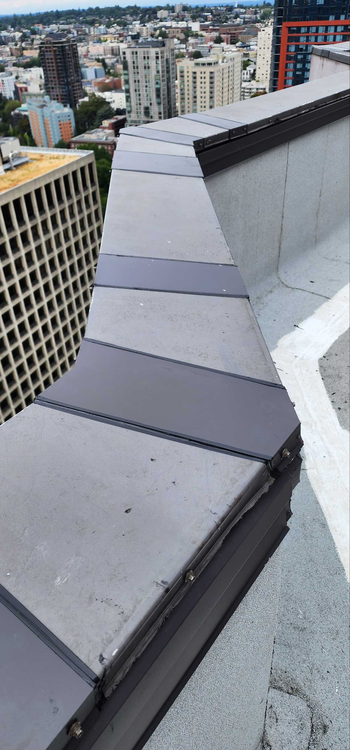 Close-up of newly installed metal coping on a flat commercial roof parapet in Seattle, showcasing clean waterproof detailing and improved edge protection.