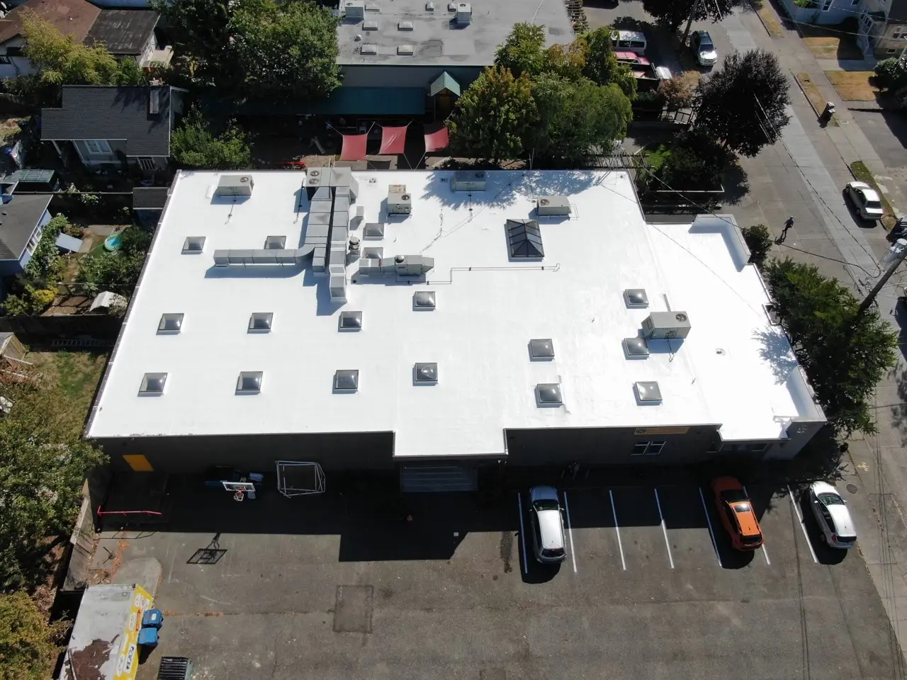 A commercial building in Seattle with a newly installed white PVC roof featuring multiple skylights and HVAC units
