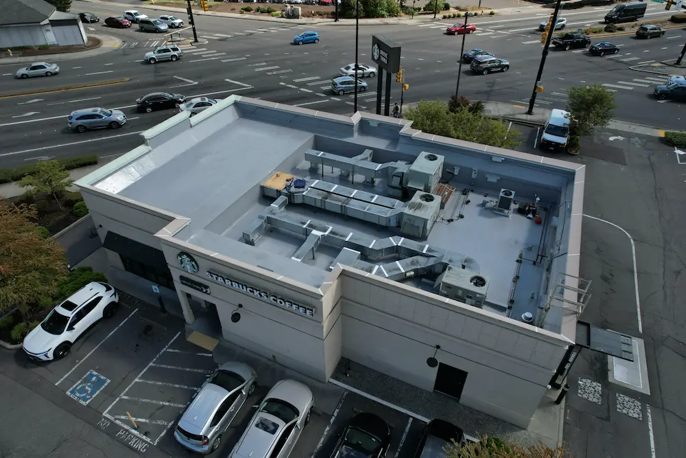 Drone view of a newly restored Starbucks commercial flat roof in Washington, showcasing a smooth, uniform membrane installation and precise finishing around complex HVAC ductwork.