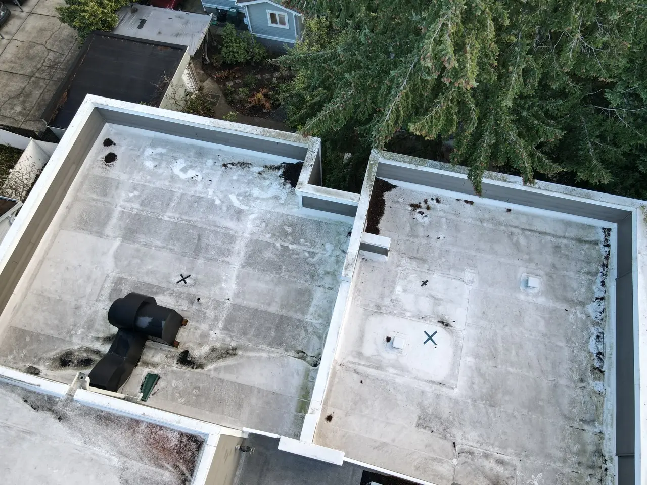 Drone photo of worn flat roof surface on a multi-unit residential building in Seattle, showing membrane damage, ponding, and aging material before full roof replacement