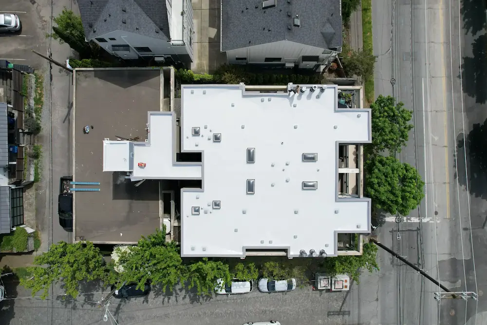 Top-down view of a newly finished and replaced multifamily flat roof with a bright, uniform membrane installed by Flat Roof Pros Inc. for long-term durability and waterproofing.