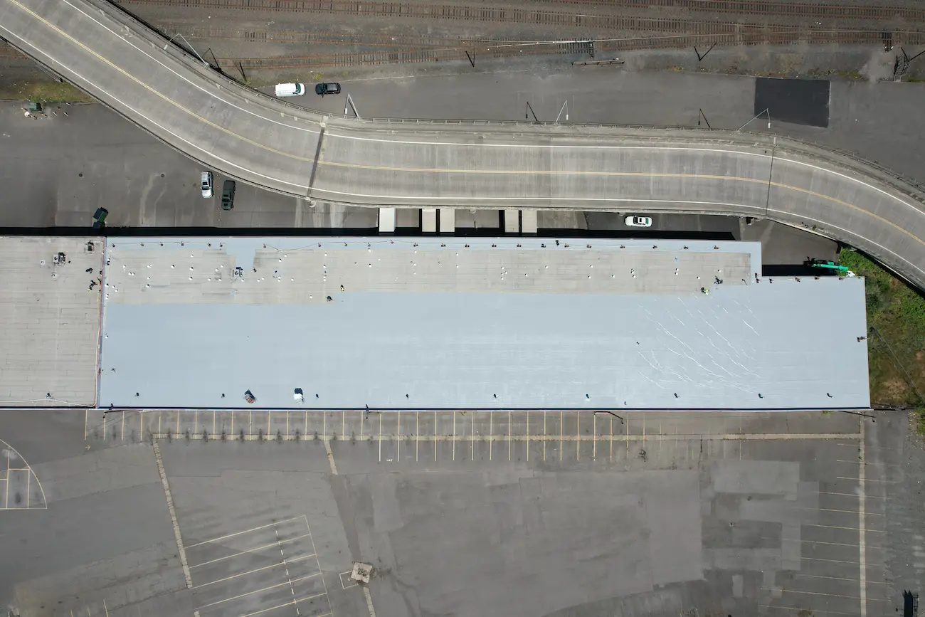 Aerial view showing half-completed silicone coating installation with restored sections visible alongside remaining uncoated areas.