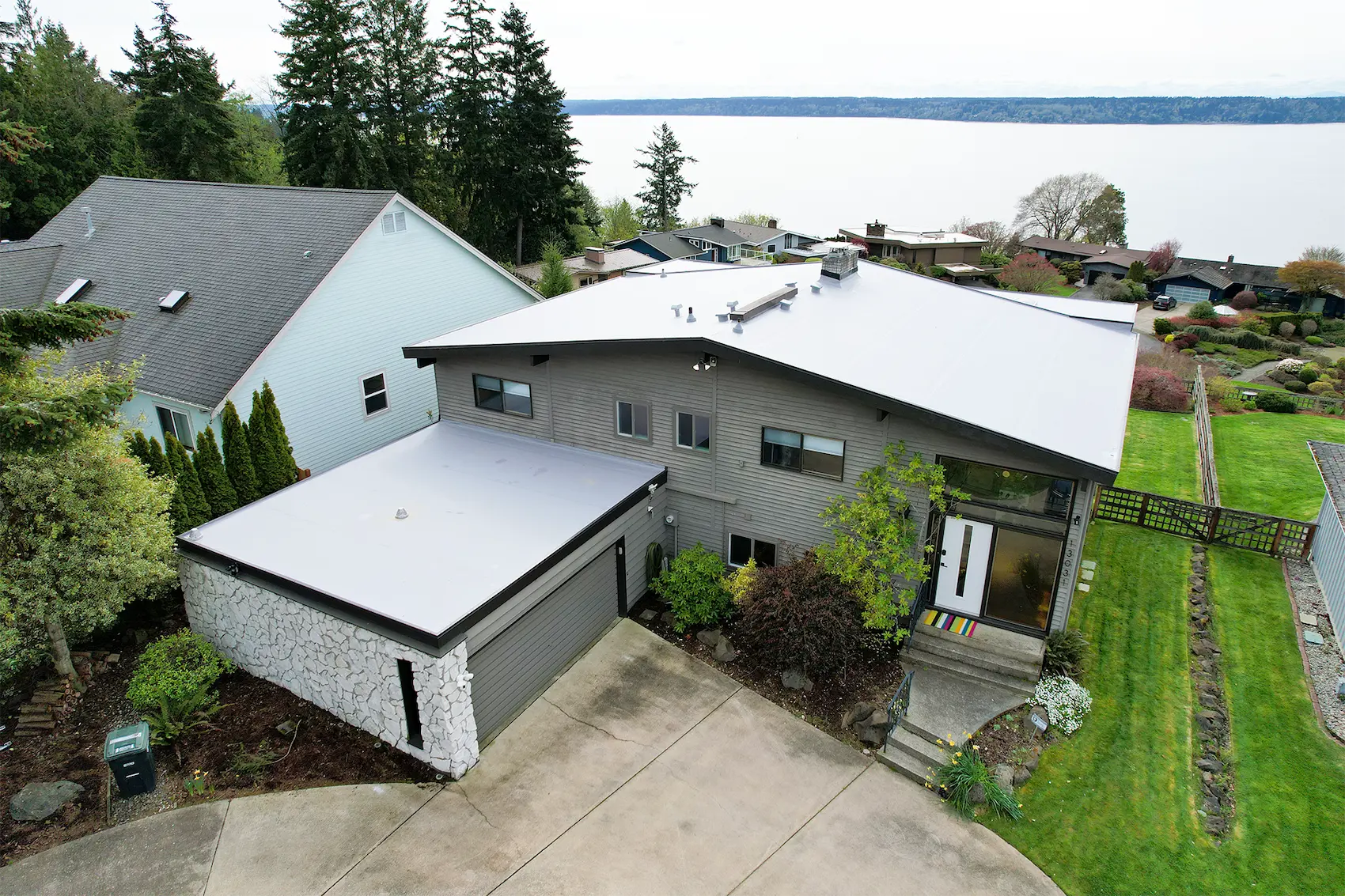 Aerial view of newly installed TPO roofing system on a residential flat roof home overlooking Puget Sound
