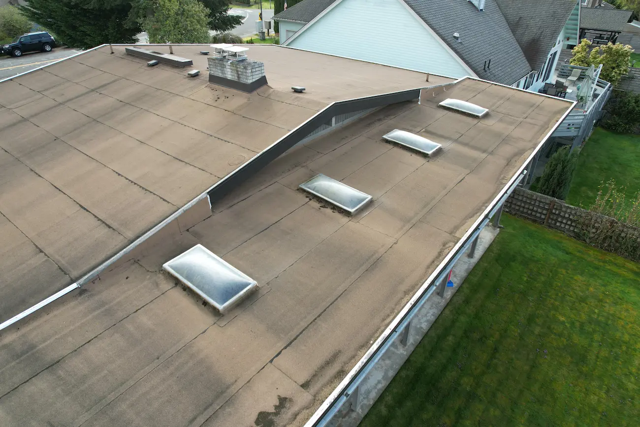 Older flat roof with skylights surrounded by deteriorated membrane and aging seam work before TPO upgrade