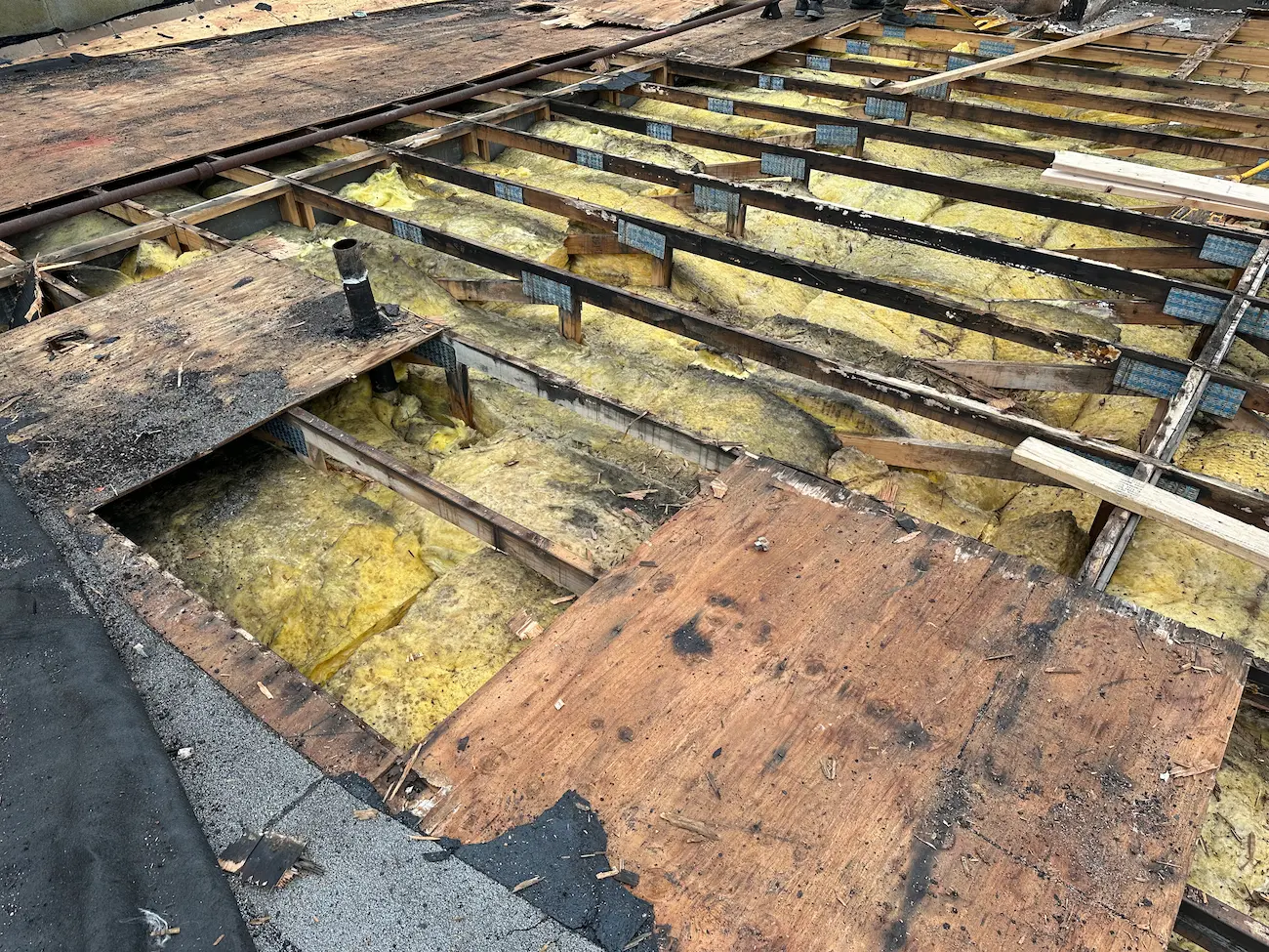 Exposed roof decking and damaged insulation revealed during tear-off phase of commercial flat roof replacement at Holiday Inn Express