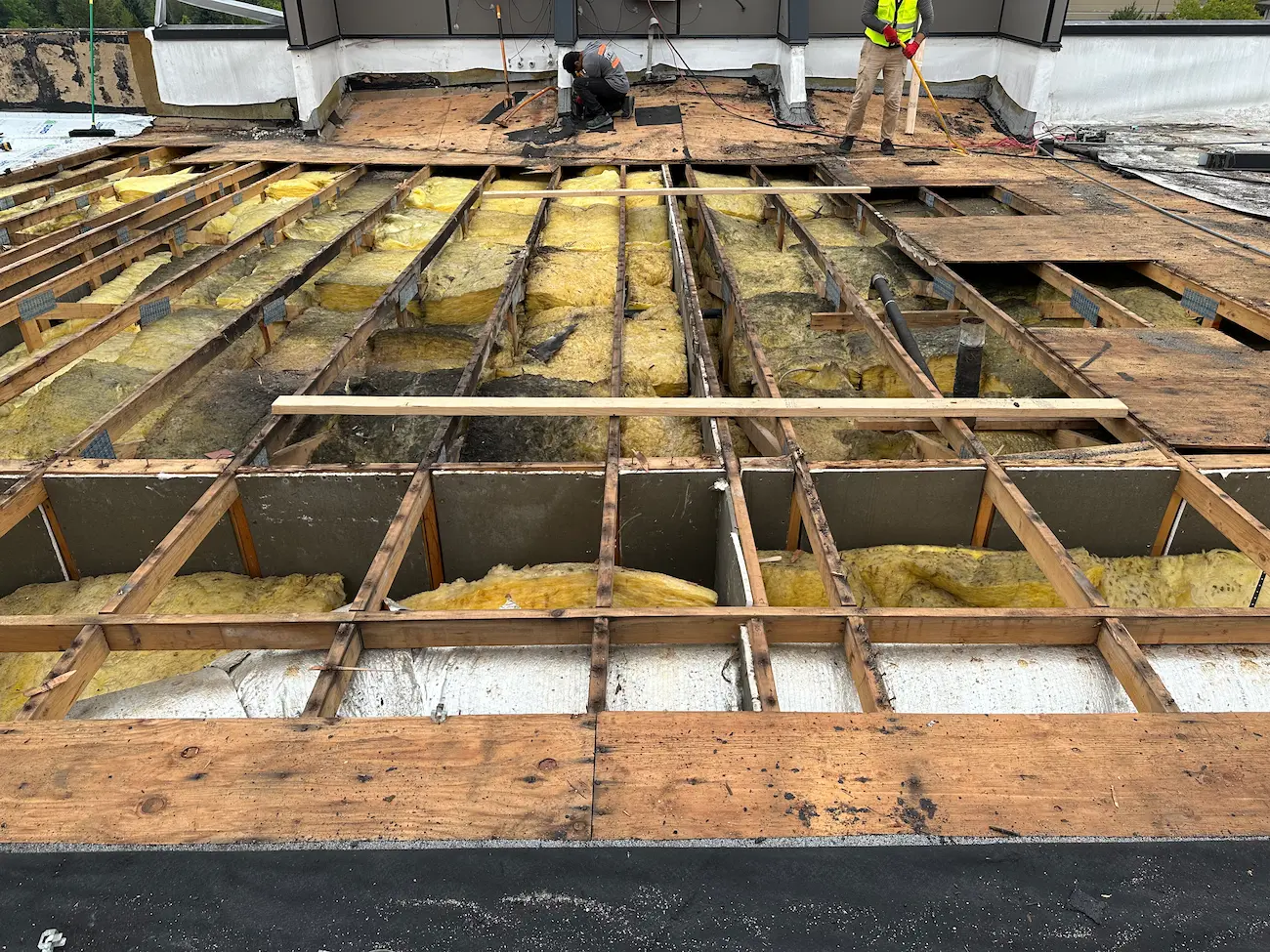 Roof tear-off exposing deteriorated insulation and framing before repairs during commercial PVC roof replacement project