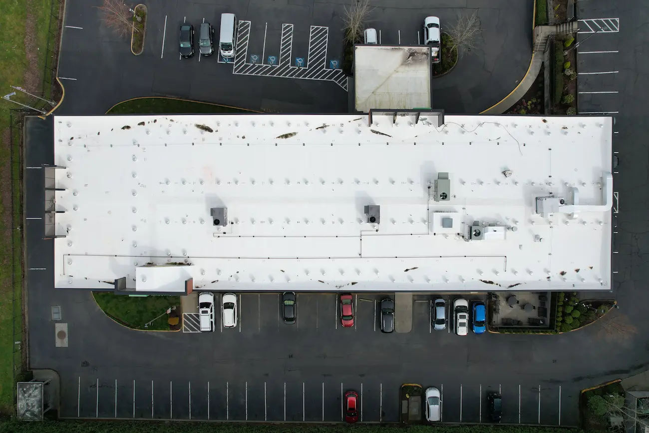 Top-down drone view of full PVC roof system on Holiday Inn Express after replacement, showing uniform field membrane and mechanical equipment layout