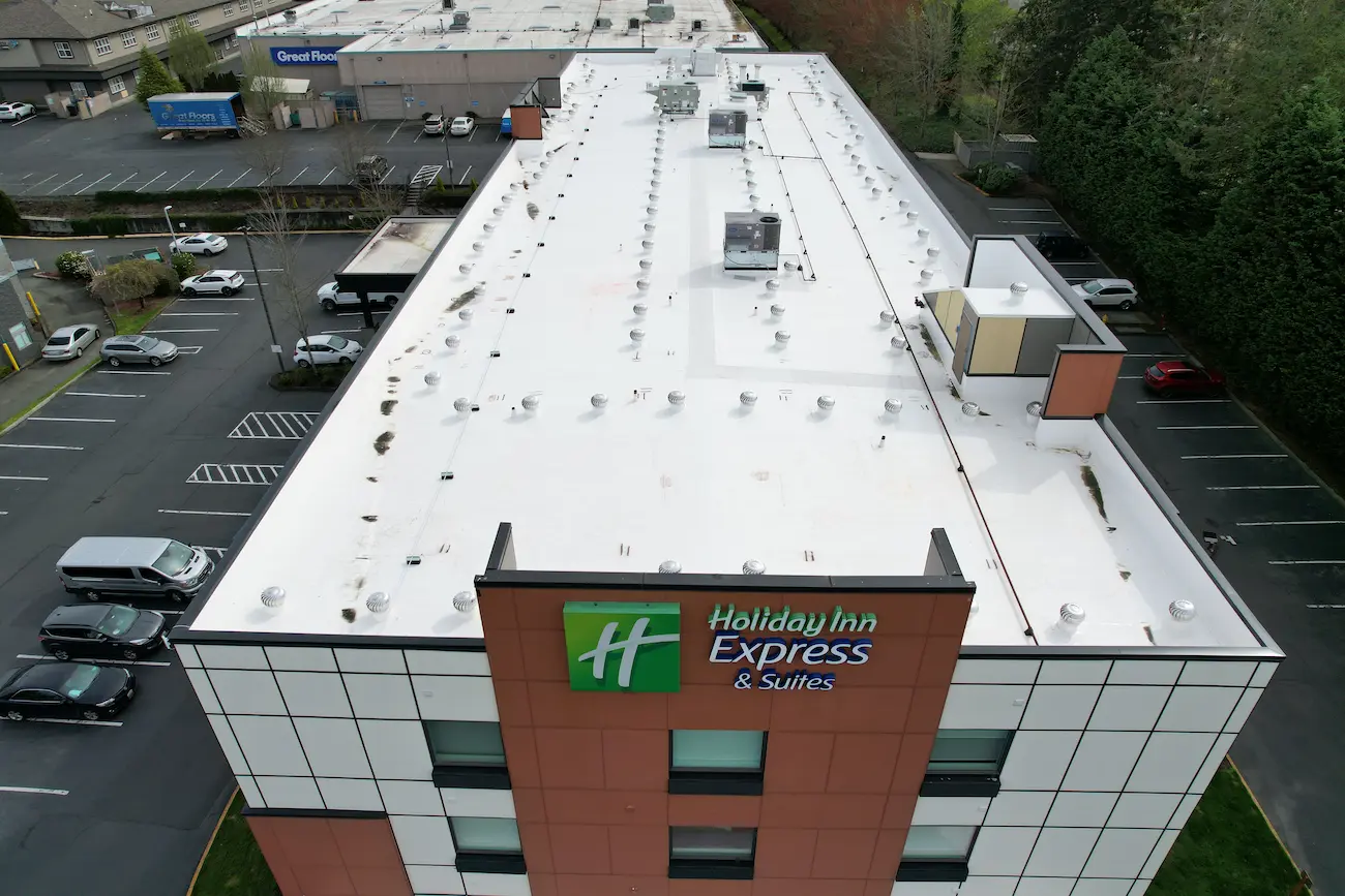 Drone image of newly installed PVC roofing on Holiday Inn Express, highlighting clean seams and upgraded ventilation across the flat roof