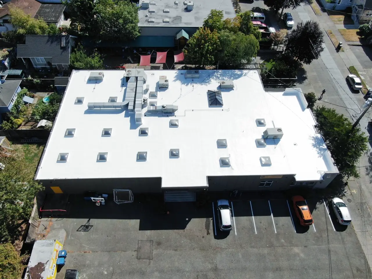 Aerial view of an aging flat roof on a K–8 school in Seattle showing signs of wear, ponding, and surface deterioration before restoration by Flat Roof Pros.
