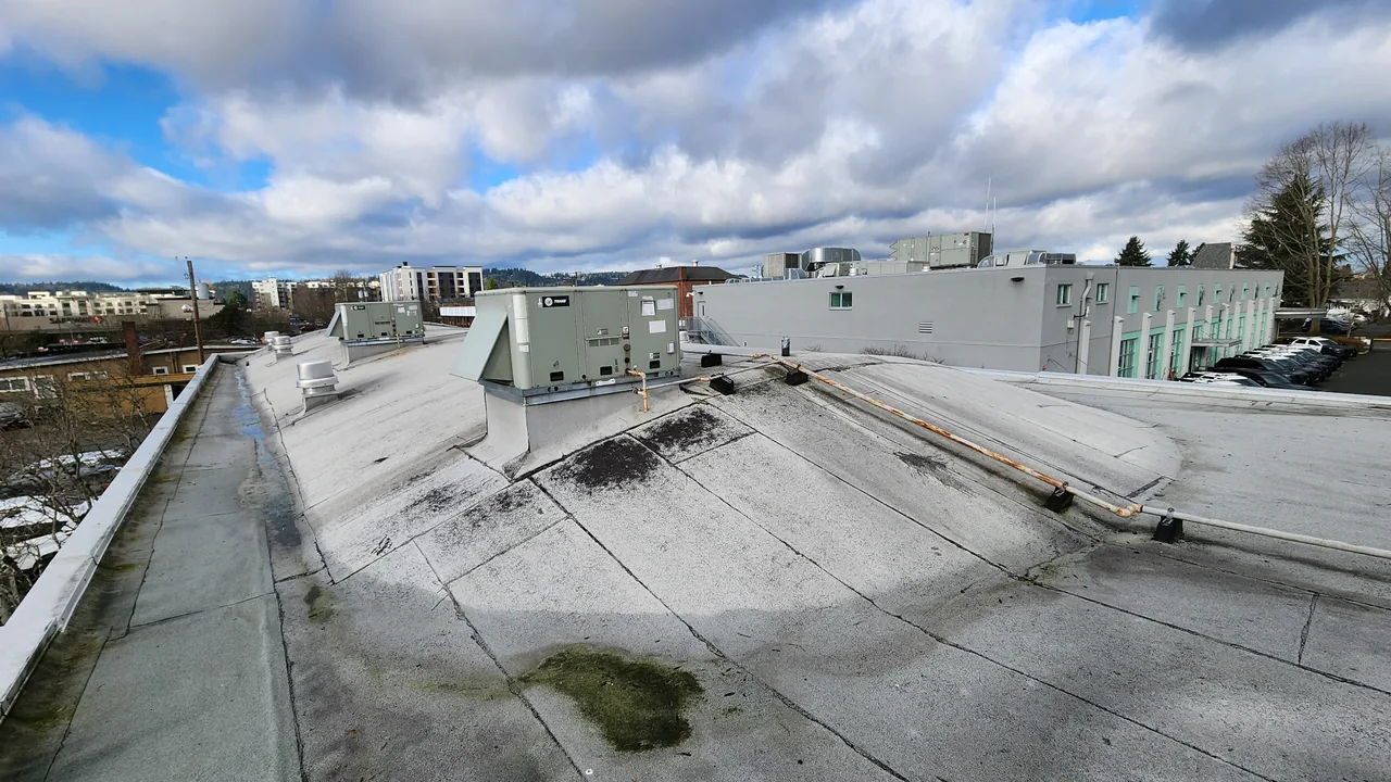 Weathered commercial flat roof photographed for a condition assessment and repair-priority report.