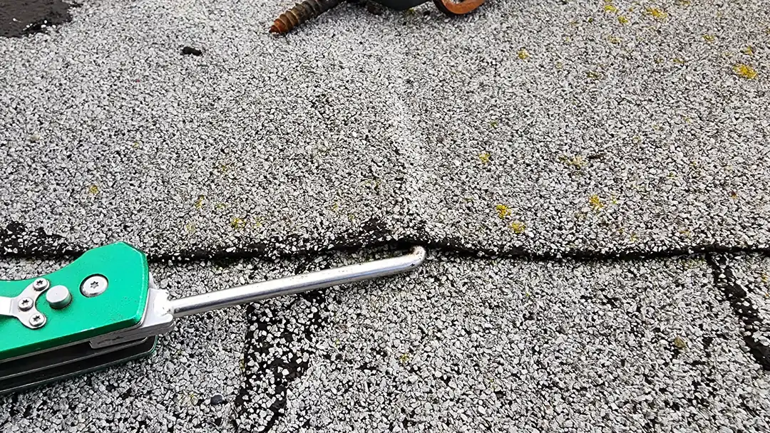A technician checking a commercial flat-roof membrane seam with a handheld inspection tool.