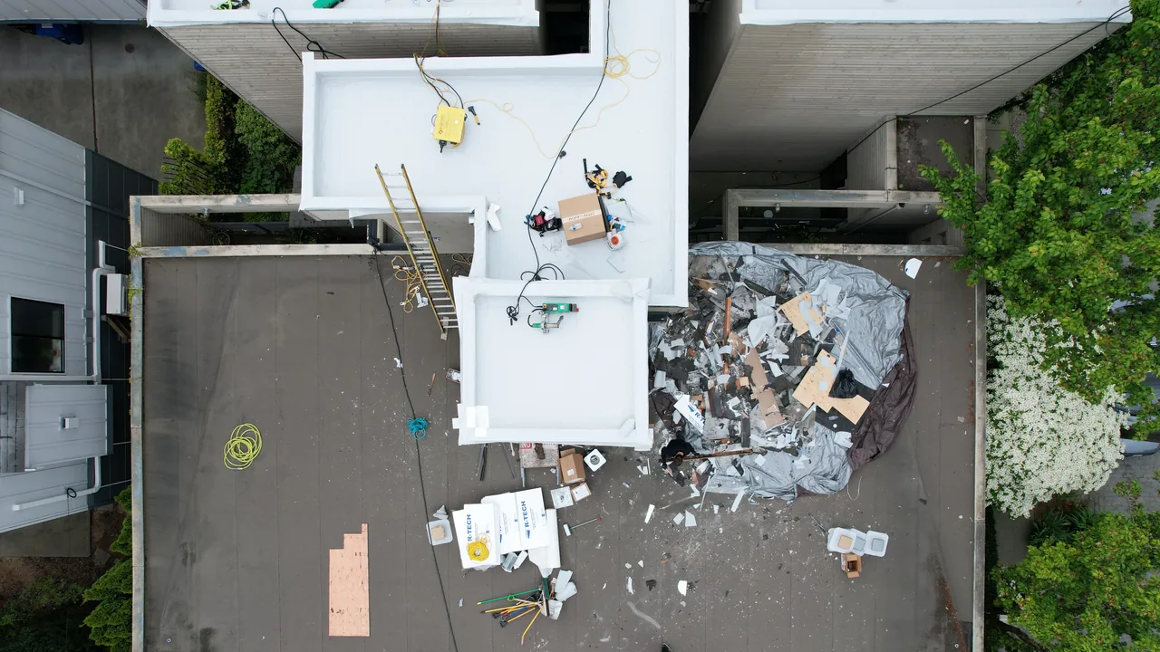 Partial roof tear-off showing an opened work area beside the remaining roof assembly.