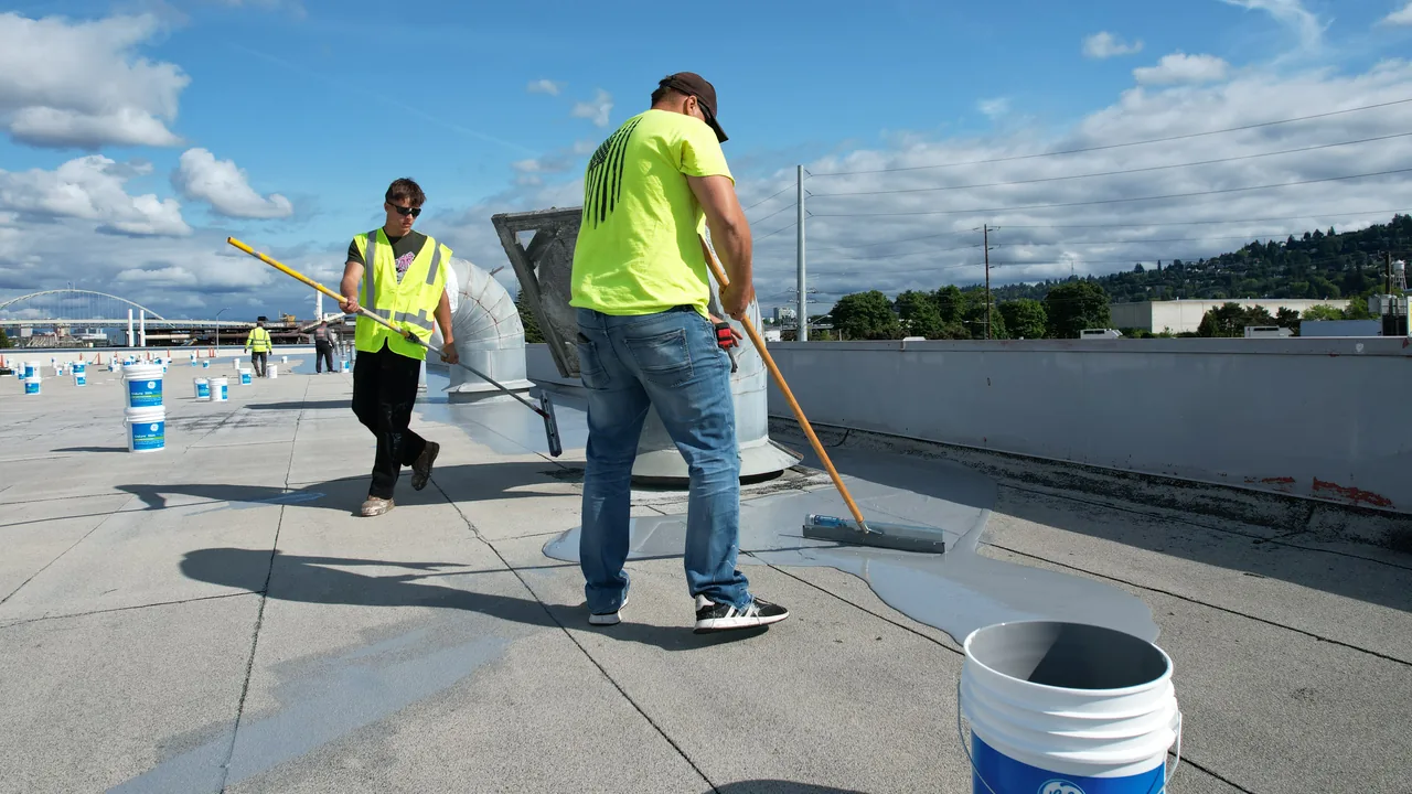 Flat Roof Pros crew applying a white restoration coating to a commercial flat roof.