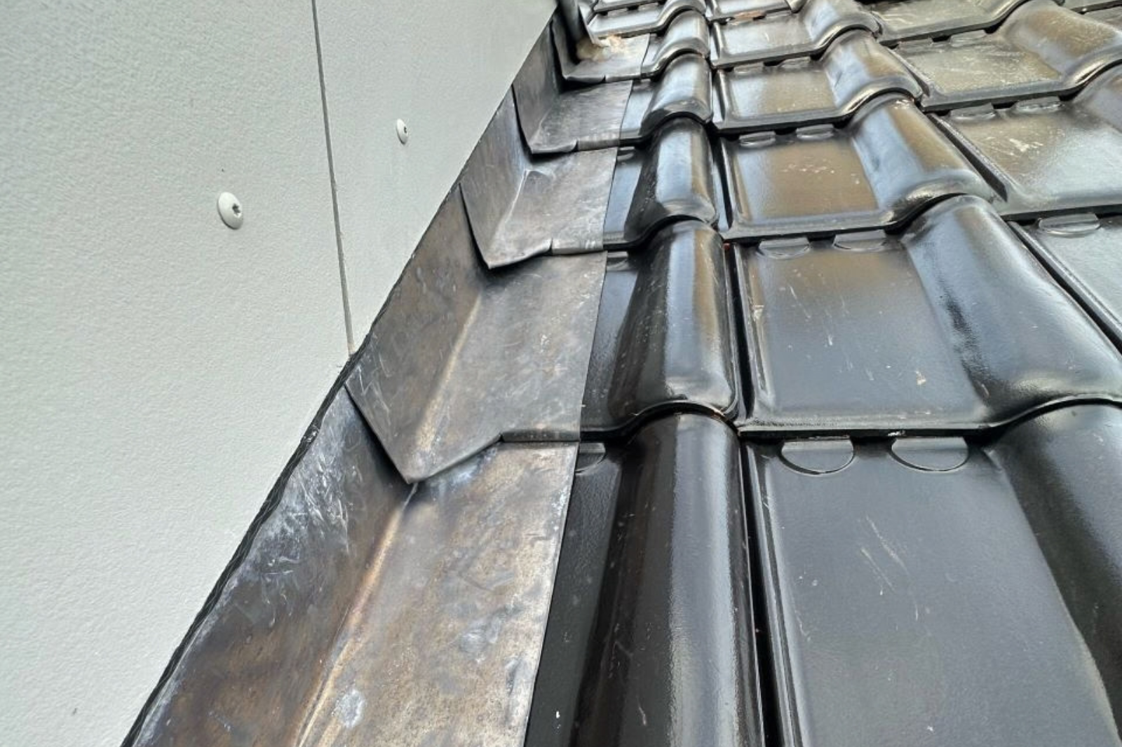 Loodslabben zorgen voor een waterdichte aansluiting tussen het pannendak en de zijgevel.