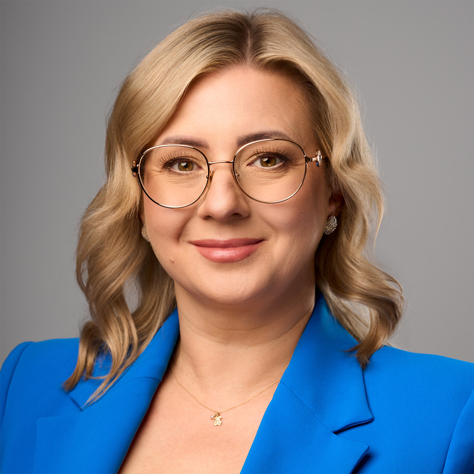 Smiling woman in blue jacket wearing glasses