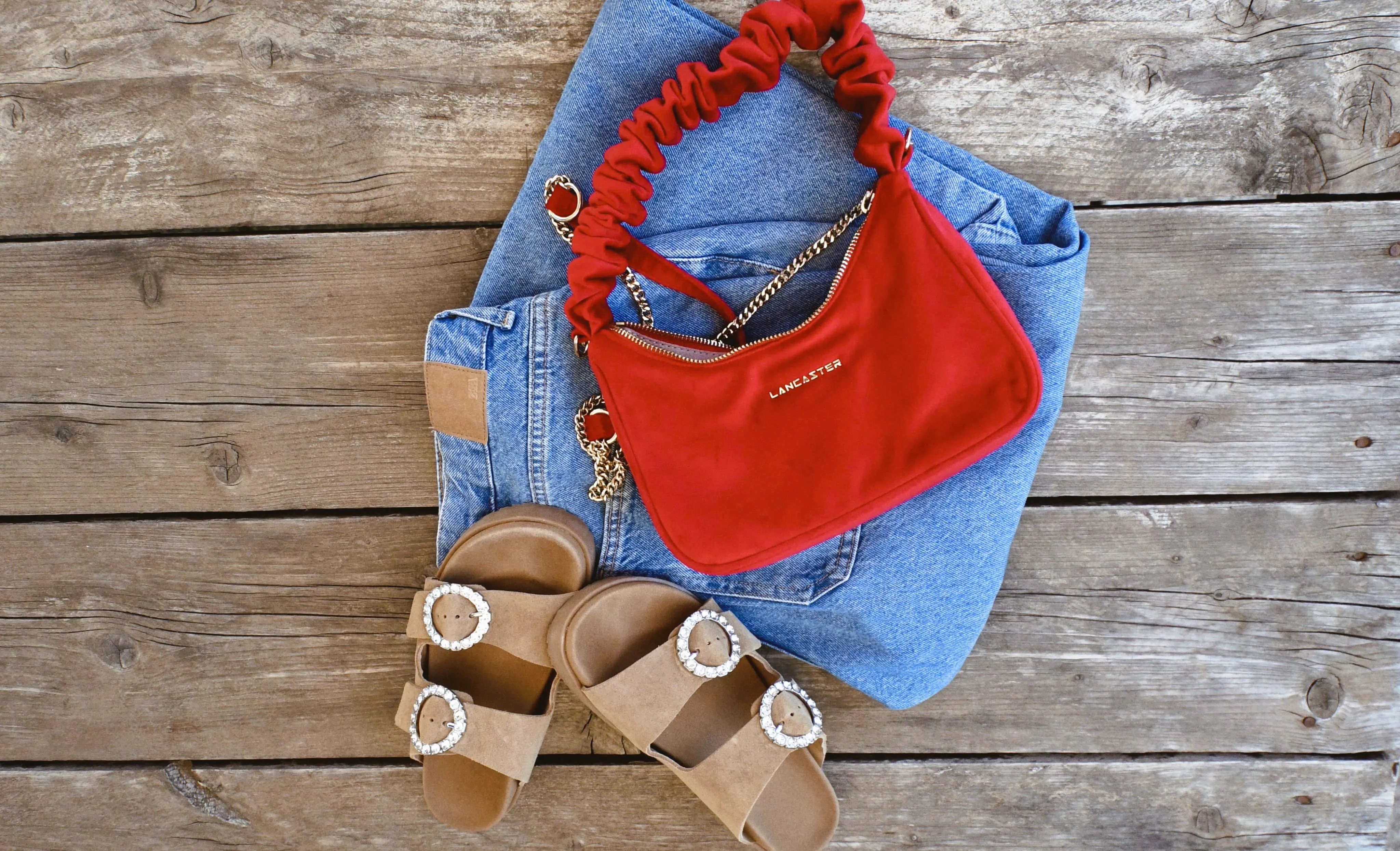 Sac rouge, jean & sandales strass sur fond en bois