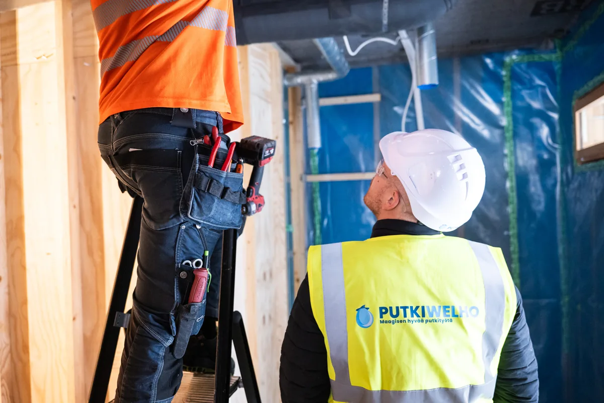 Putkiwelhon asentajat työskentelevät rakennuskohteessa.