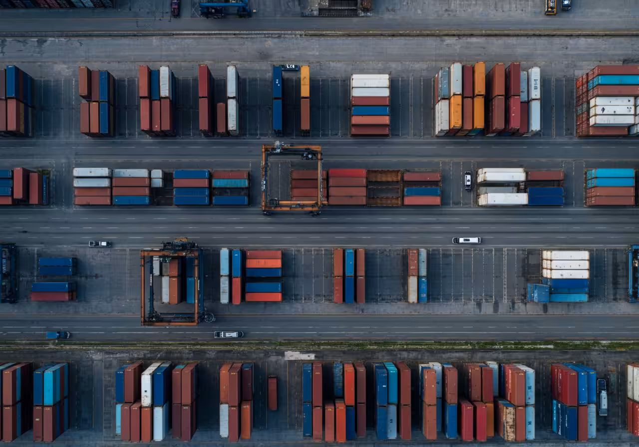Bird’s-eye view of neatly arranged, multicolored shipping containers at a busy port facility.
