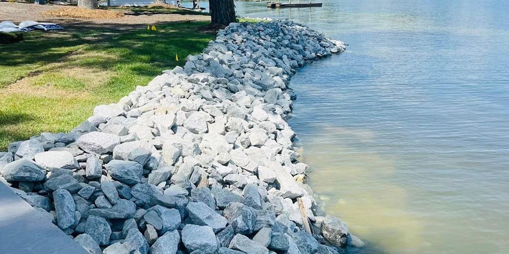 A close up  on the shoreline, made up of evenly and cleanly placed white rocks.