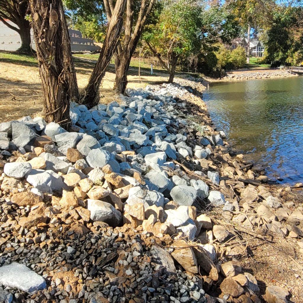 A nice looking sandy shoreline with a wall of white rocks edging the shore.