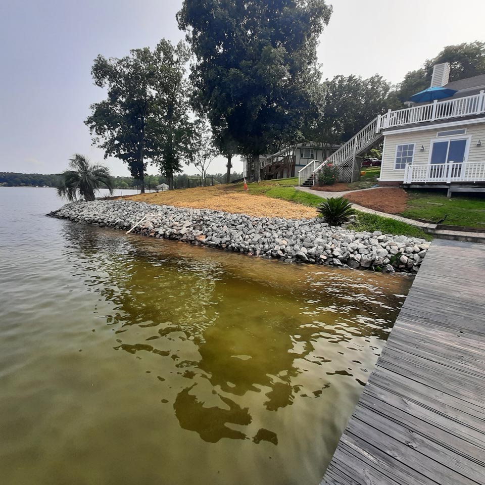 A cleaned up shoreline with weed removal and new rocks.