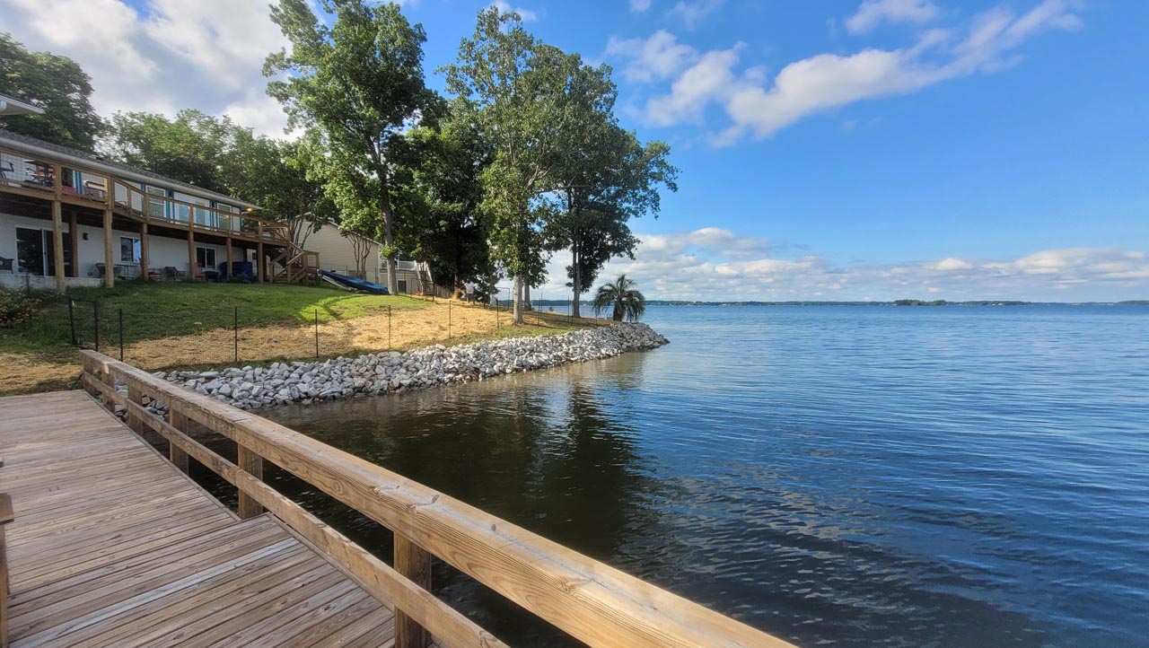 A view of the lakeshore from a dock, clean and well maintained shoreline with beautiful rock wall.