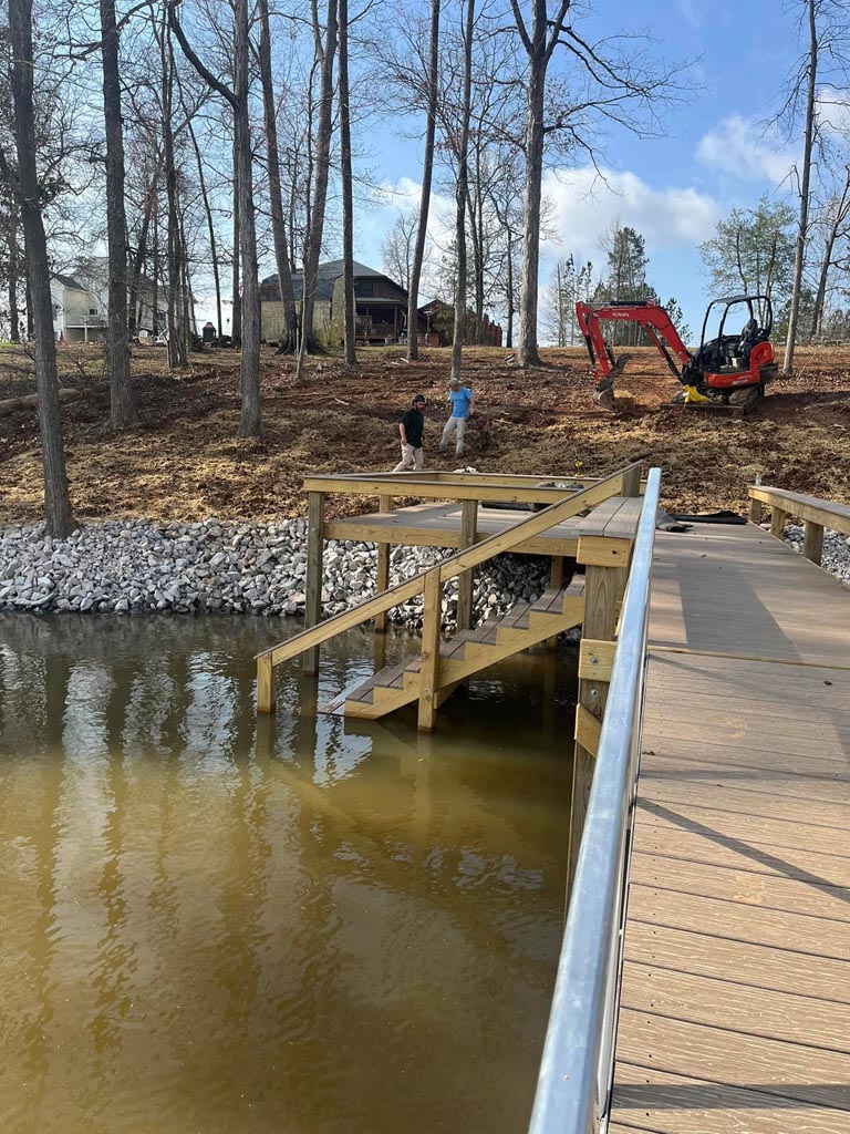 A brand new shoreline installed with grading and lot cleaning work happening in the background.