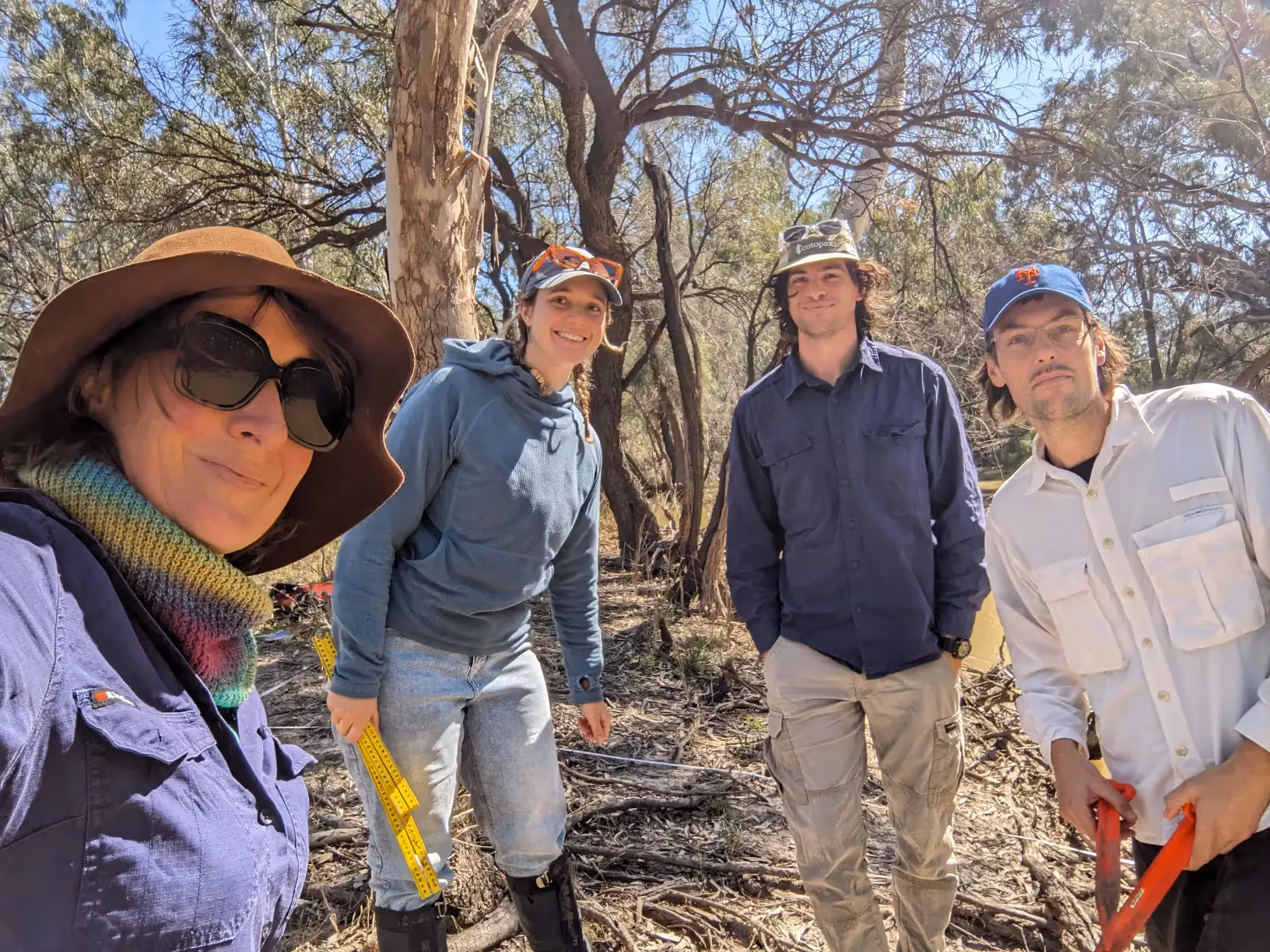 Four people looking at the camera with trees behind.