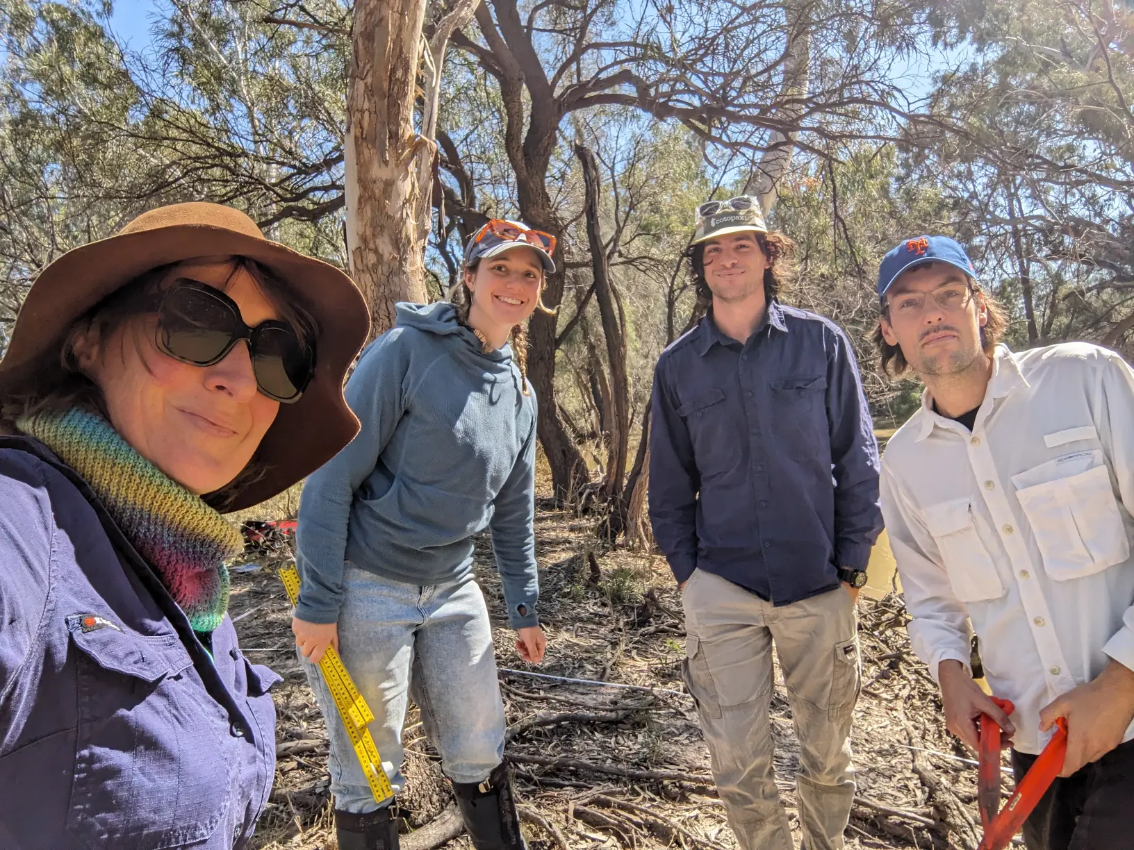 Four people looking at the camera with trees behind.