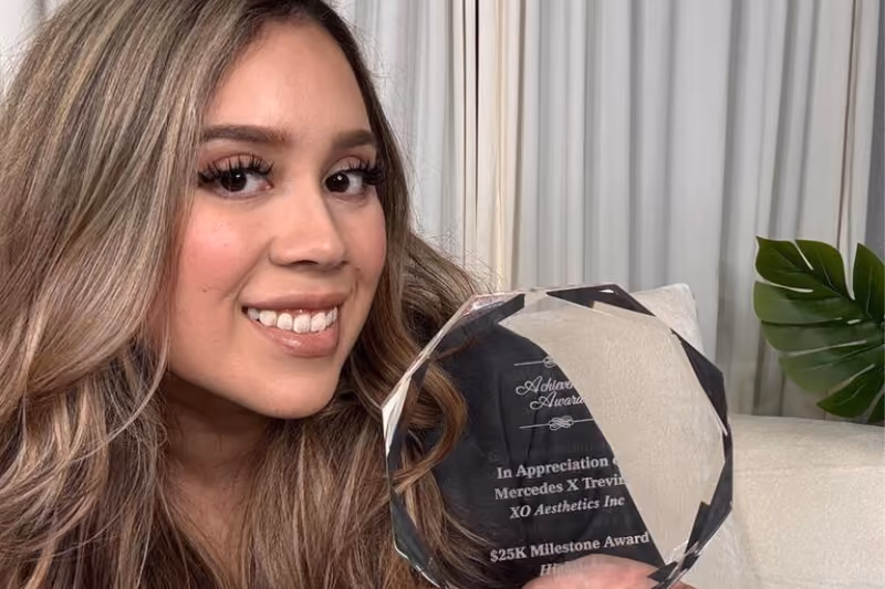 Smiling woman holding her milestone achievement trophy at Highstoke