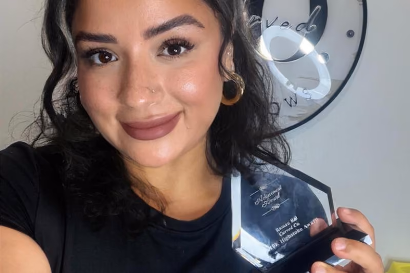 Smiling woman holding a glass achievement award from Highstoke