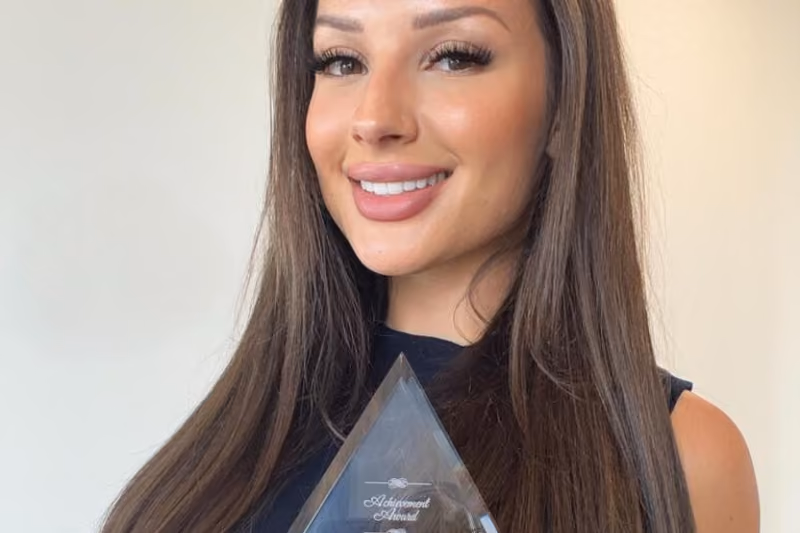 Smiling woman holding a glass achievement award at Highstoke