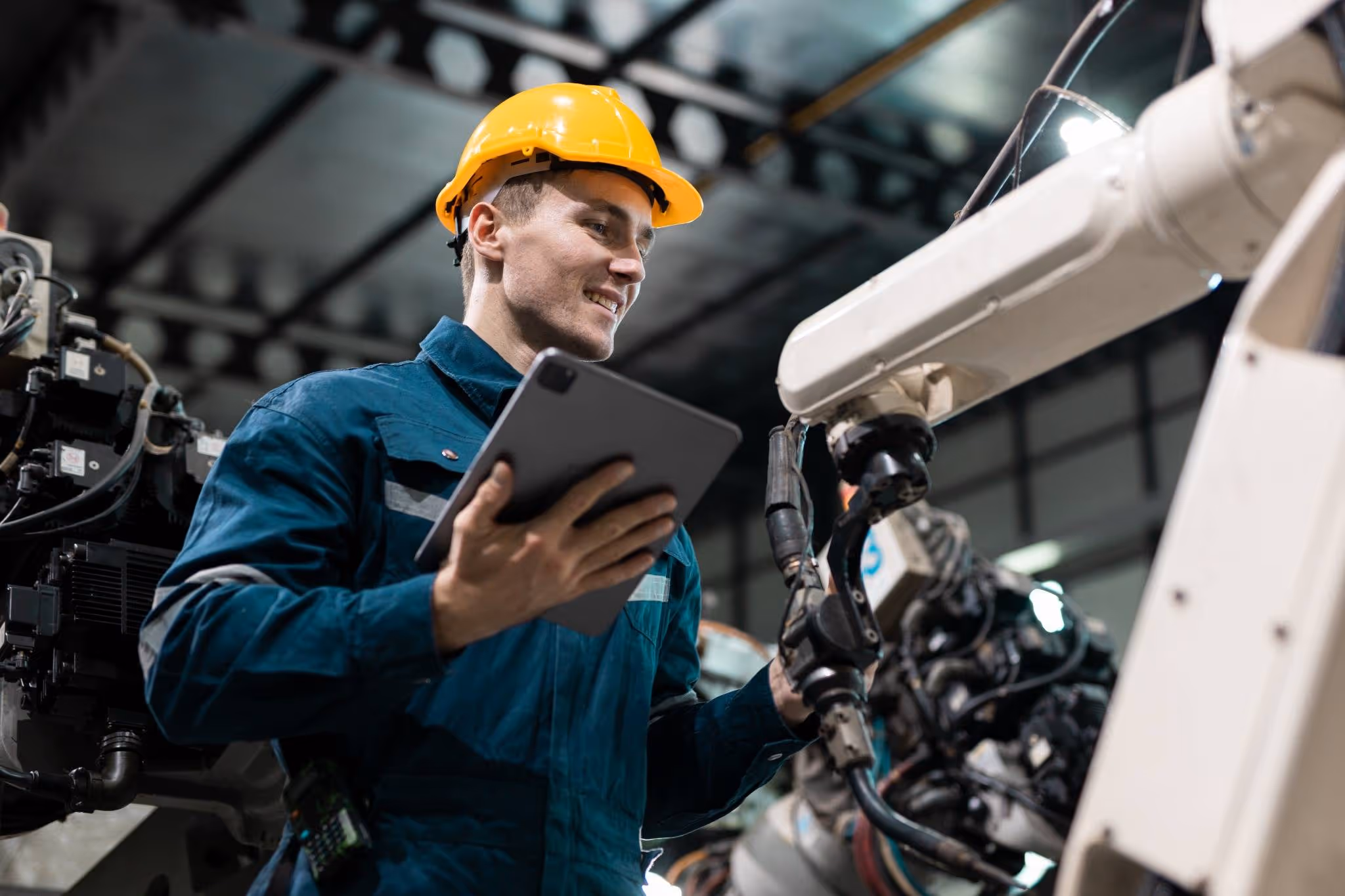 Man working on maintenance of equipment wearing a hard hat and using a tablet device