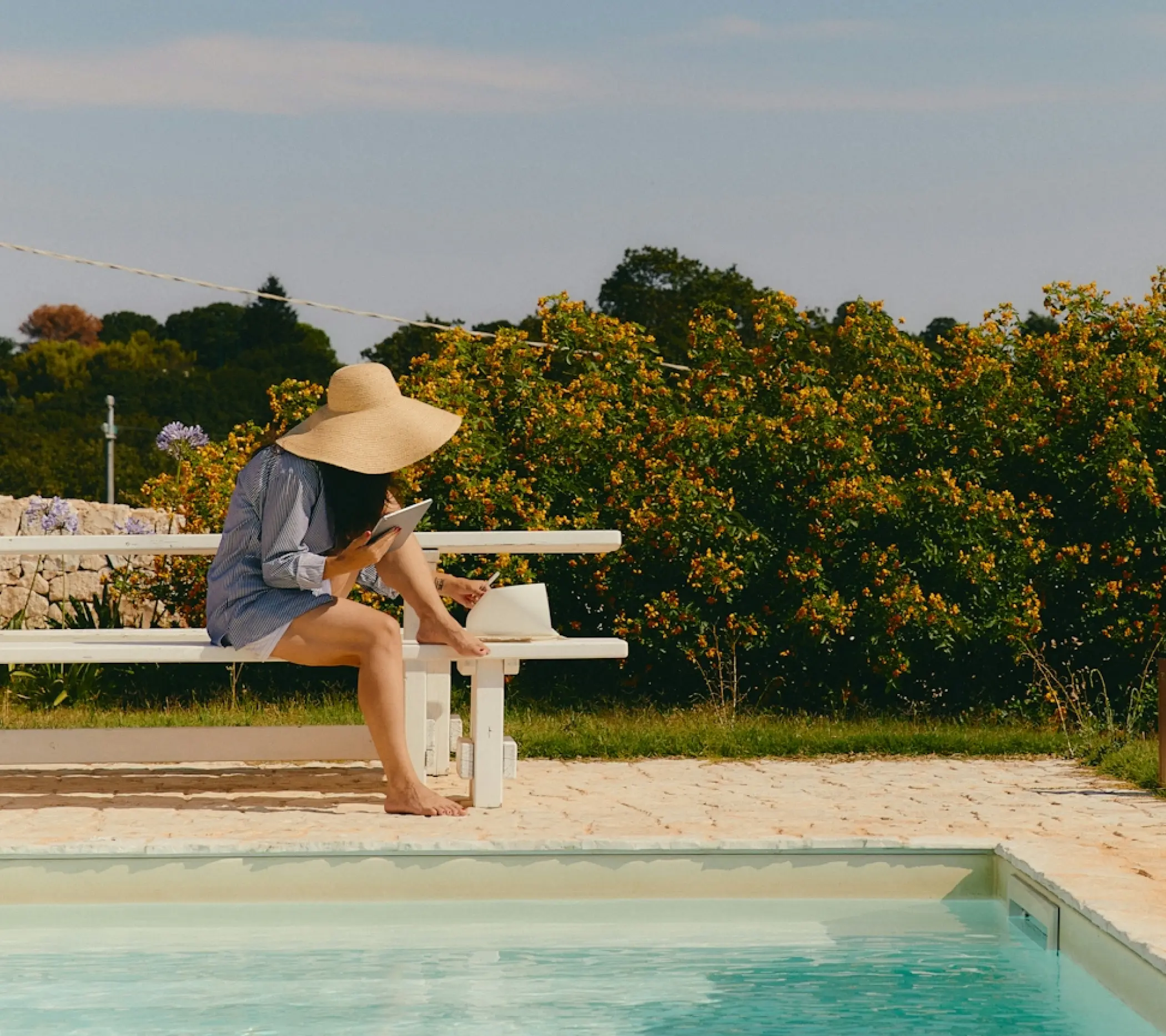 A woman sitting on a bench beside a tranquil pool, enjoying the serene atmosphere.