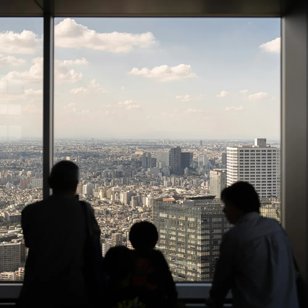 family with teen staring out of a window with of view of tokyo city