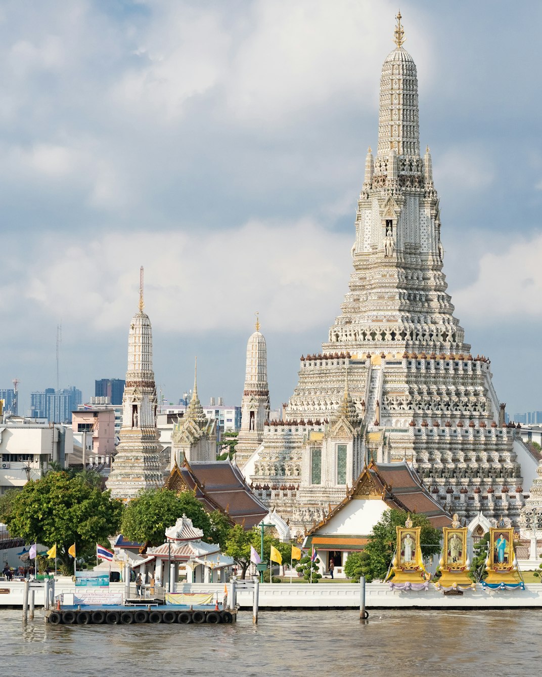 Wat Arun temple on the Chao Phraya river in Bangkok under a cloudy sky