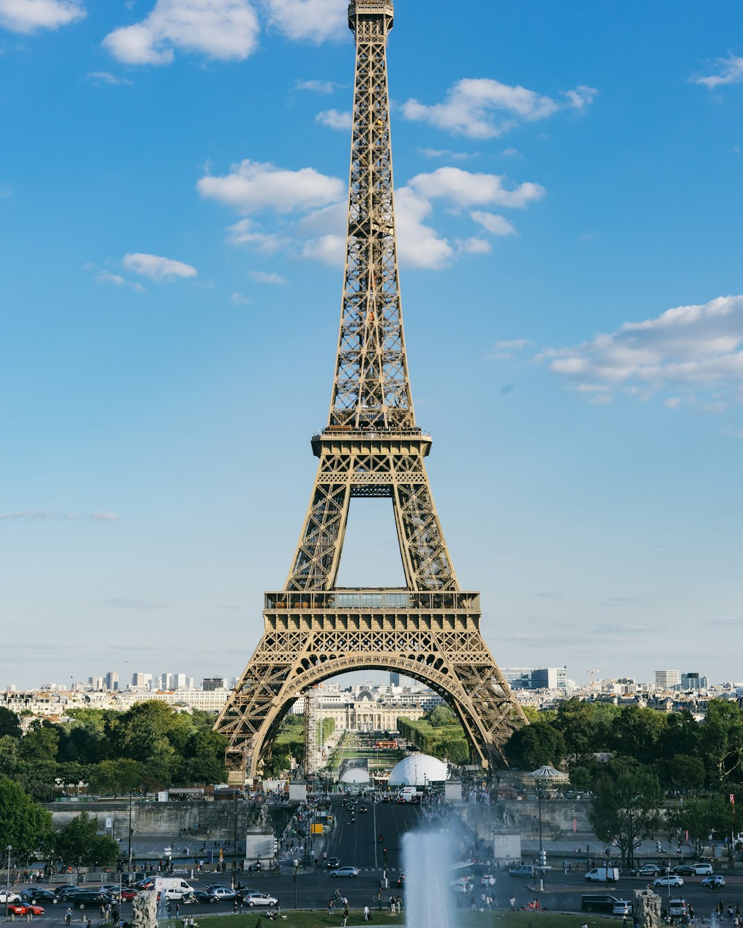The Eiffel Tower rising above Paris under a blue sky with light clouds