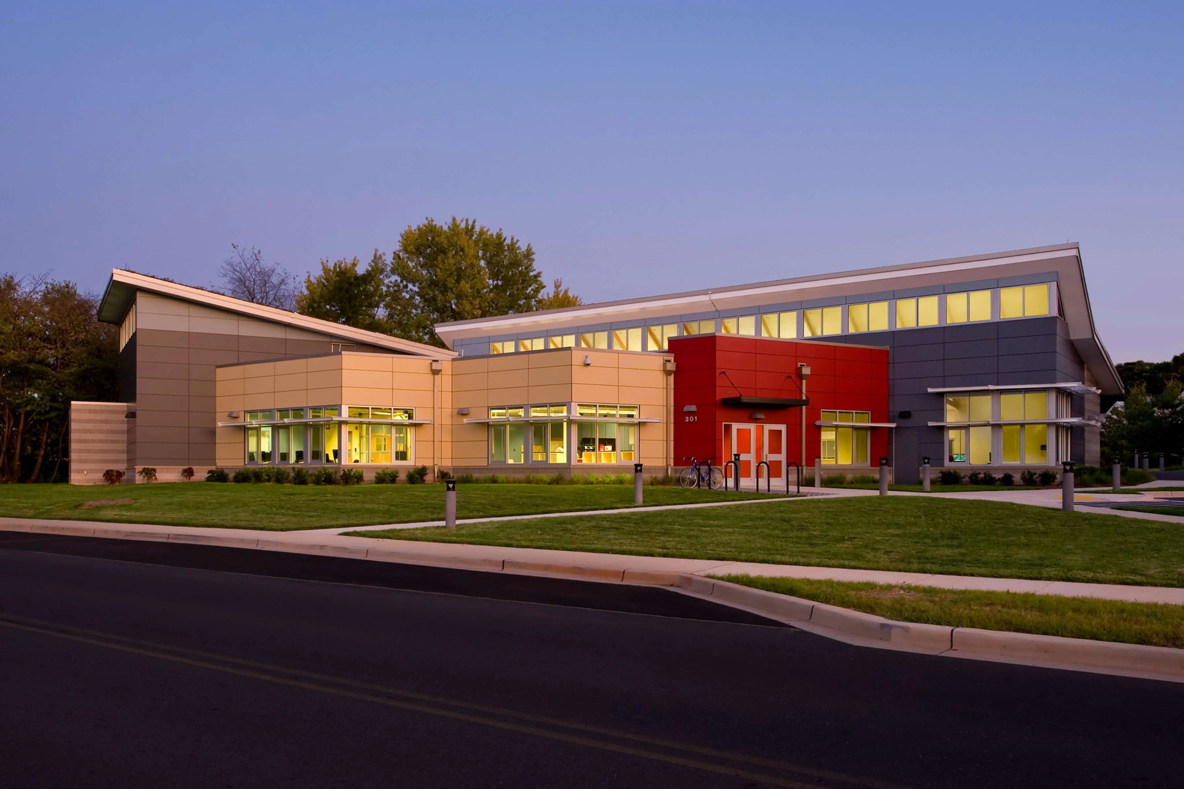 Modern educational building featuring vibrant colors and large windows, surrounded by green landscaping.
