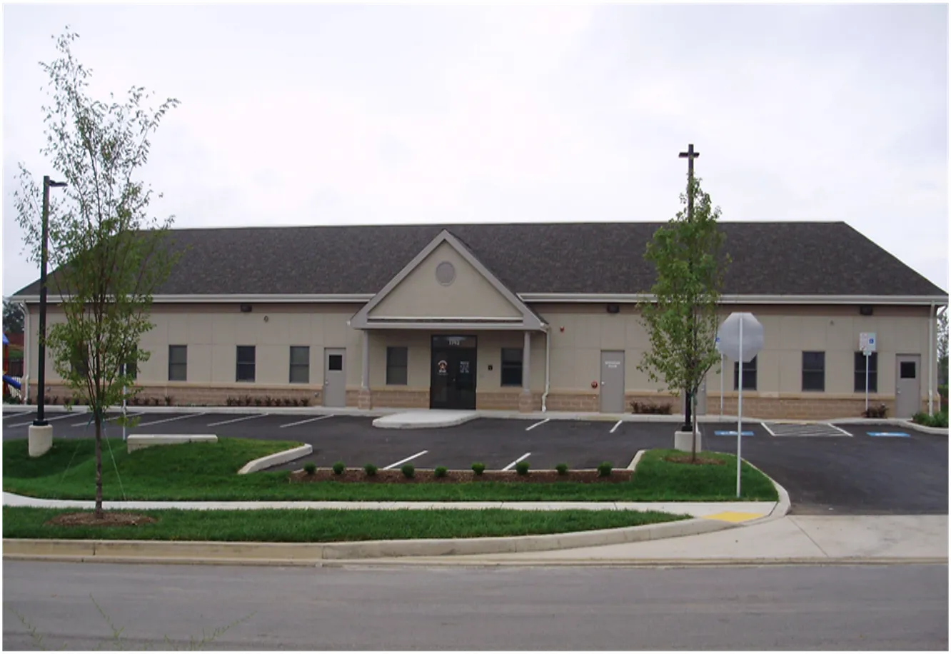 Exterior of a modern church building featuring a prominent cross and well-maintained landscaping.
