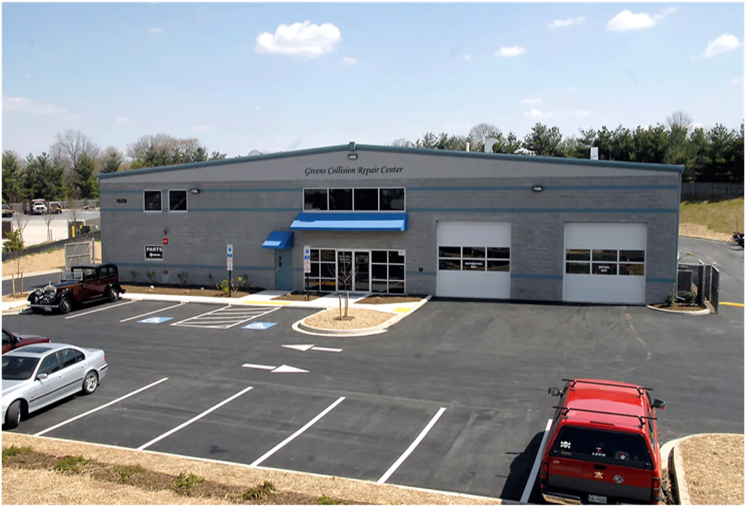 Givens Collision Repair Center exterior with parking lot and entrance visible on a sunny day.
