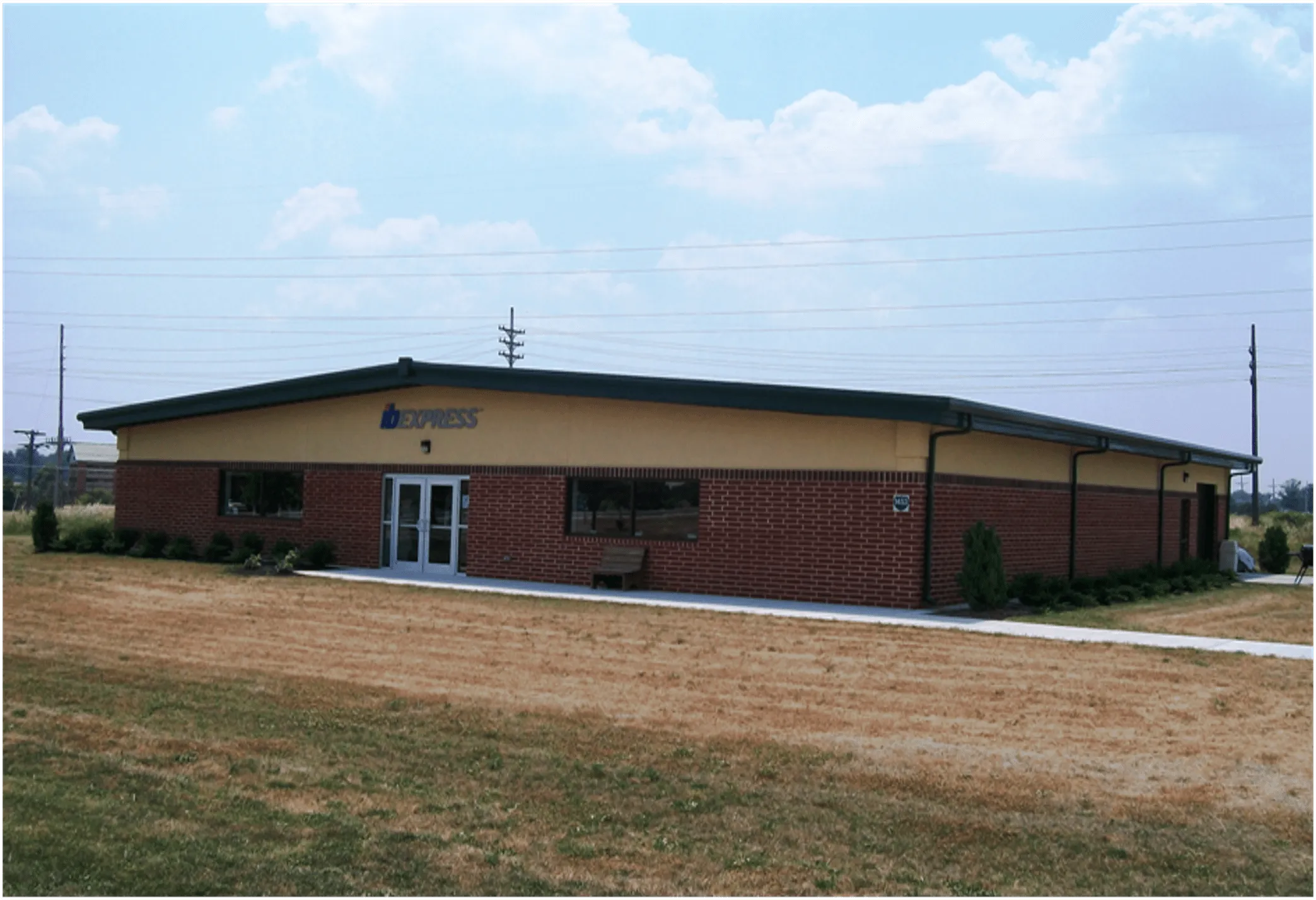 Express building with a welcoming entrance, surrounded by grassy areas and blue sky.
