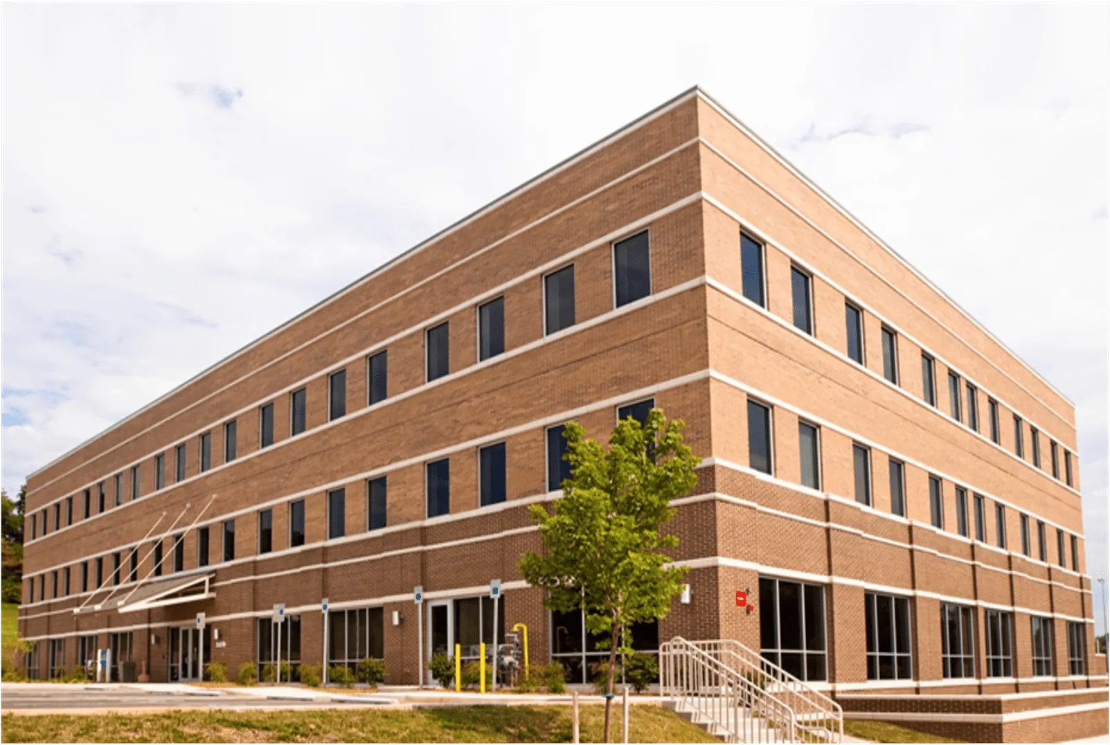Modern brick office building featuring large windows and landscaped entrance.
