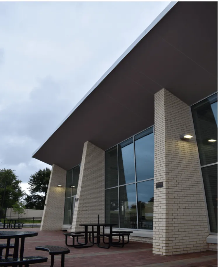 Modern building exterior featuring large windows and outdoor seating area.

