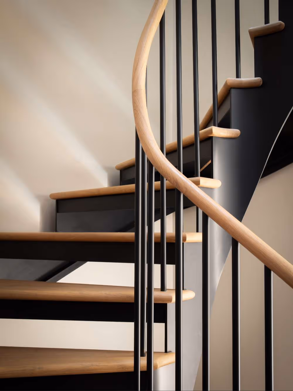 bespoke, curved, pale oak tread, metal staircase with black metal spindle balustrade