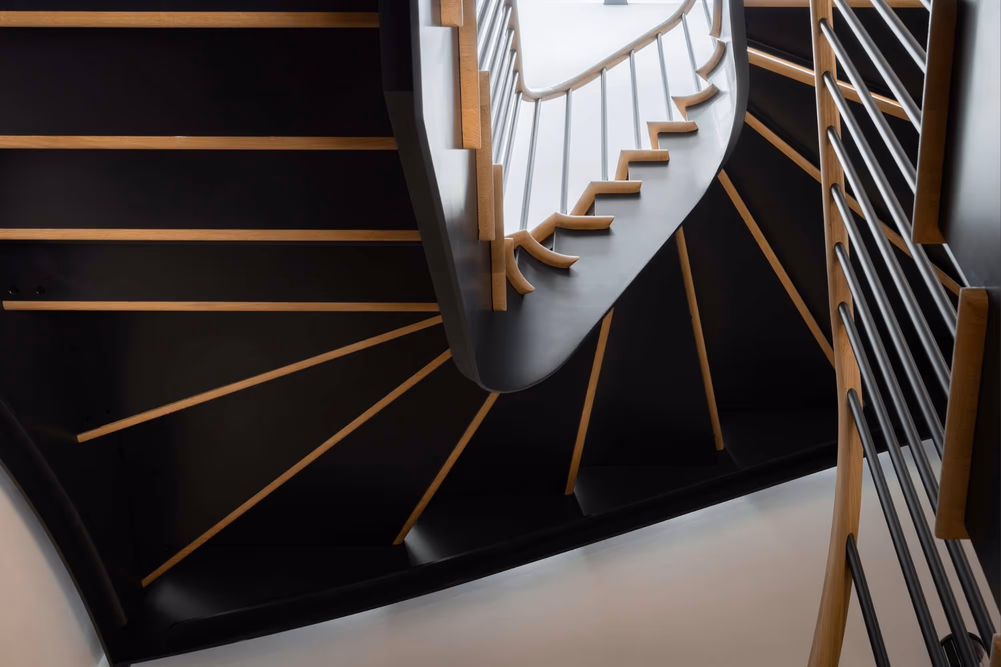 bespoke, curved, pale oak tread, metal staircase with black metal spindle balustrade