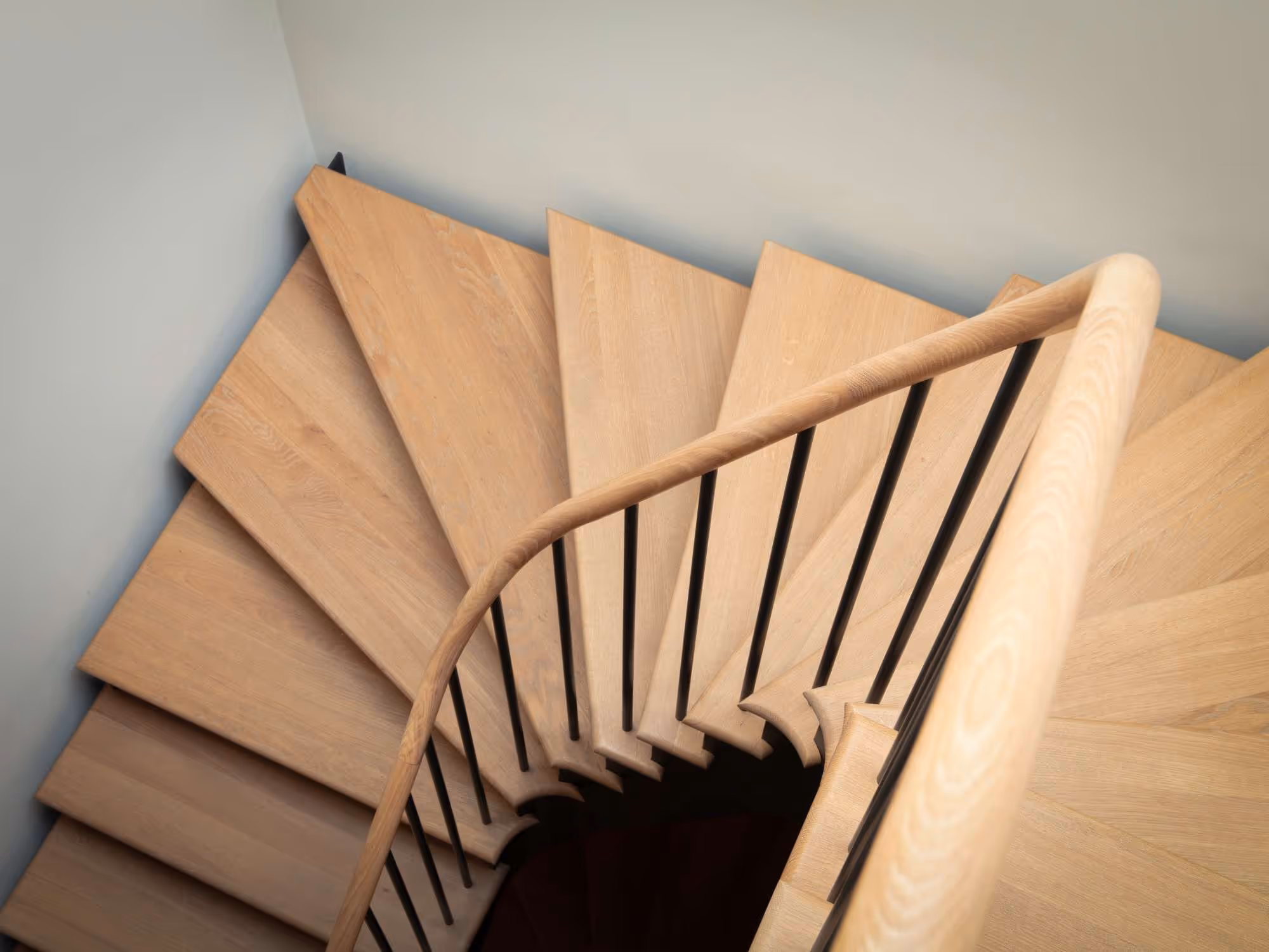 bespoke, curved, pale oak tread, metal staircase with black metal spindle balustrade