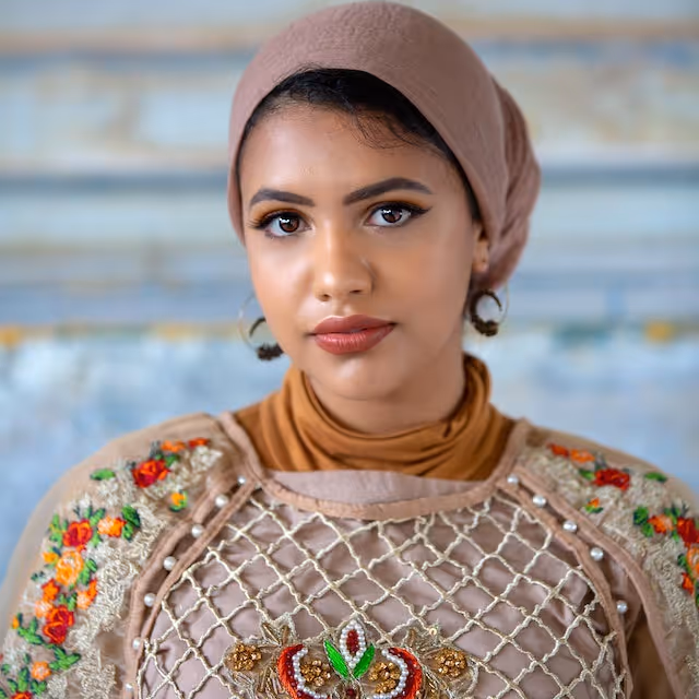 Woman in embroidered hijab and traditional dress with floral shoulder details