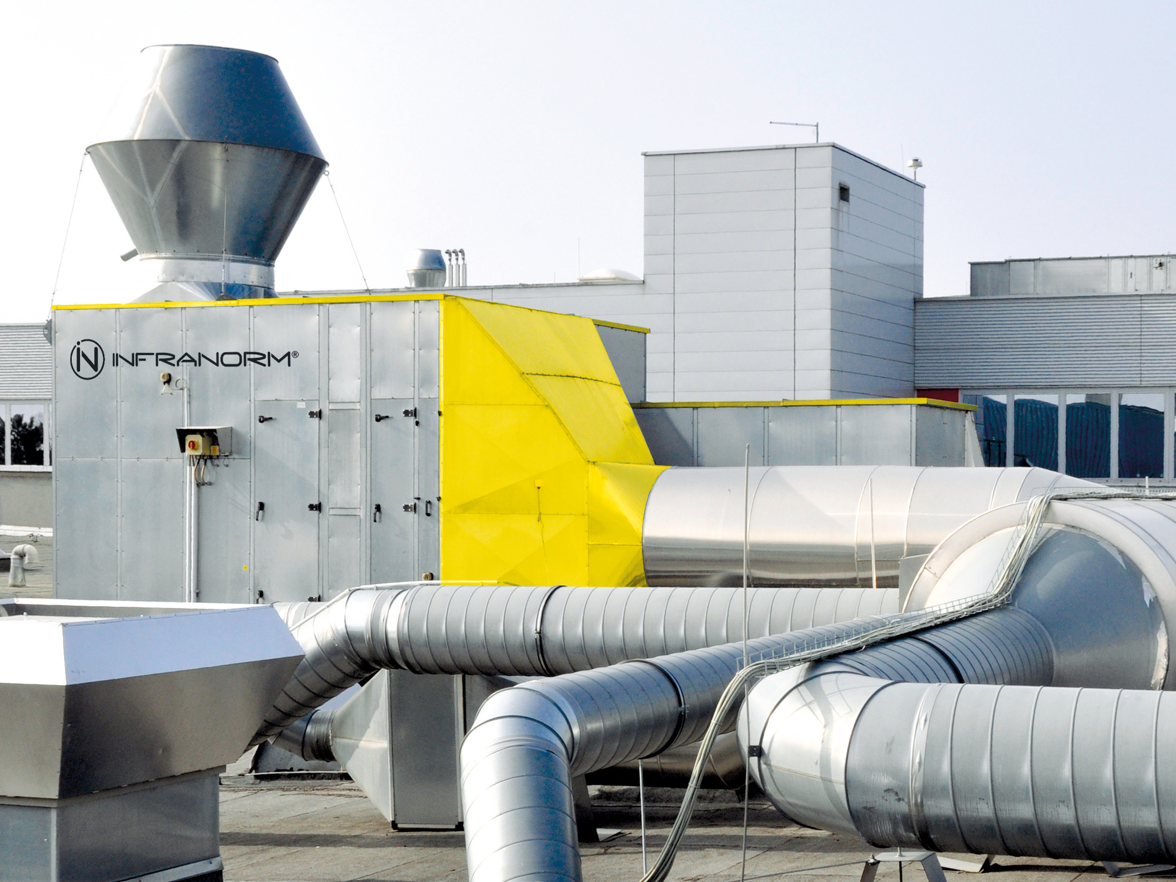 Industrie-Dachanlage mit gelbem Luftkanal und INFRANORM-Lüftungssystemen